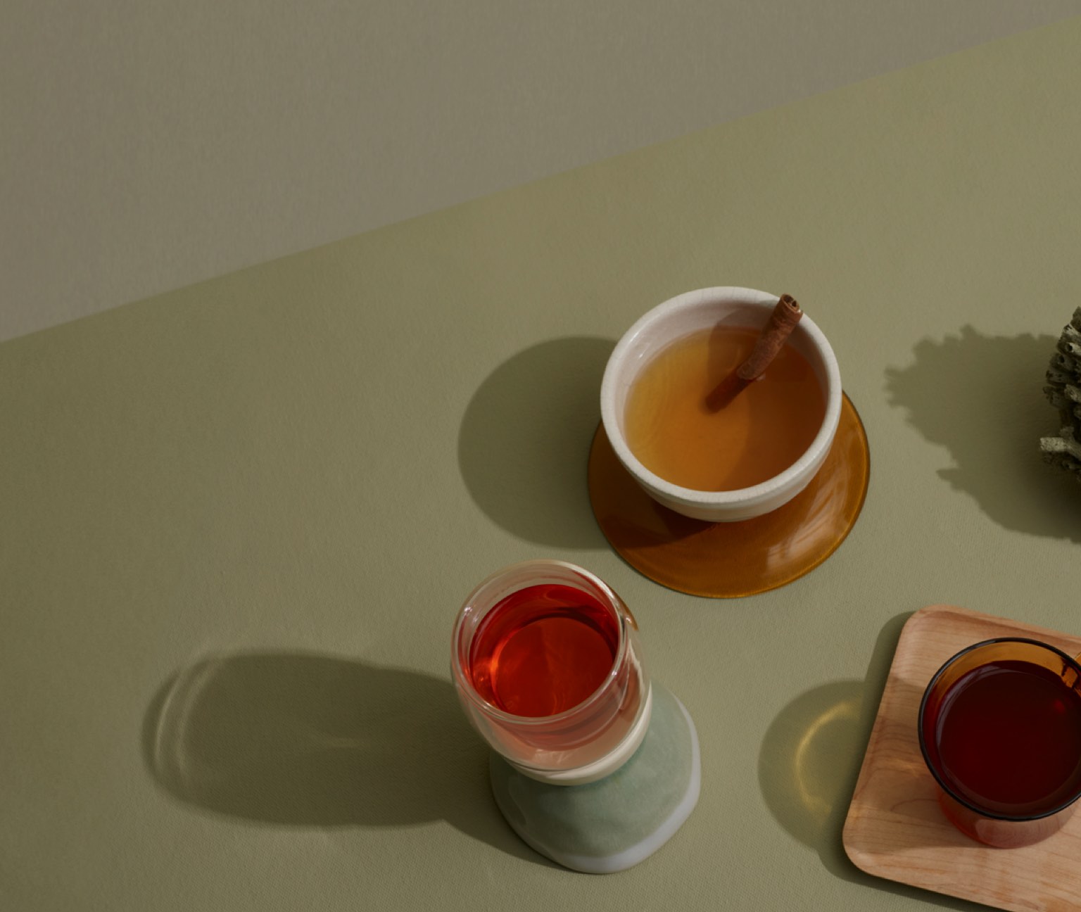Assortiment de tasses en verre et en céramique remplies de thé chaï à base d’ingrédients tels que gingembre, anis et cardamome.