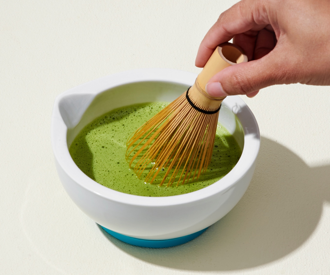 A whisk and bowl filled with matcha.