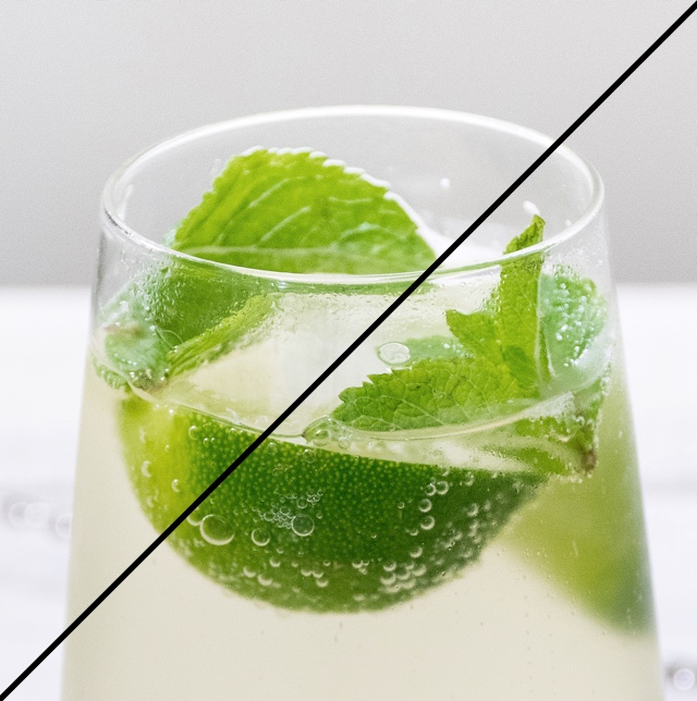 A glass filled with a drink, slice of lime and mint.