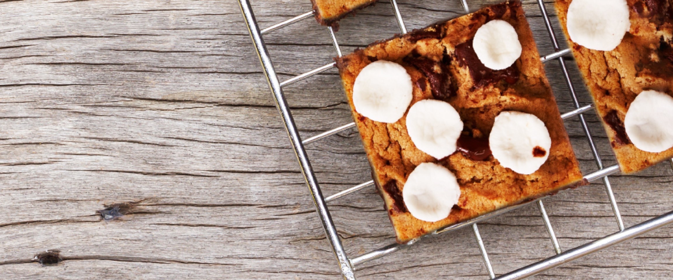 S’mores blondie squares topped with marshmallows on cooling rack.