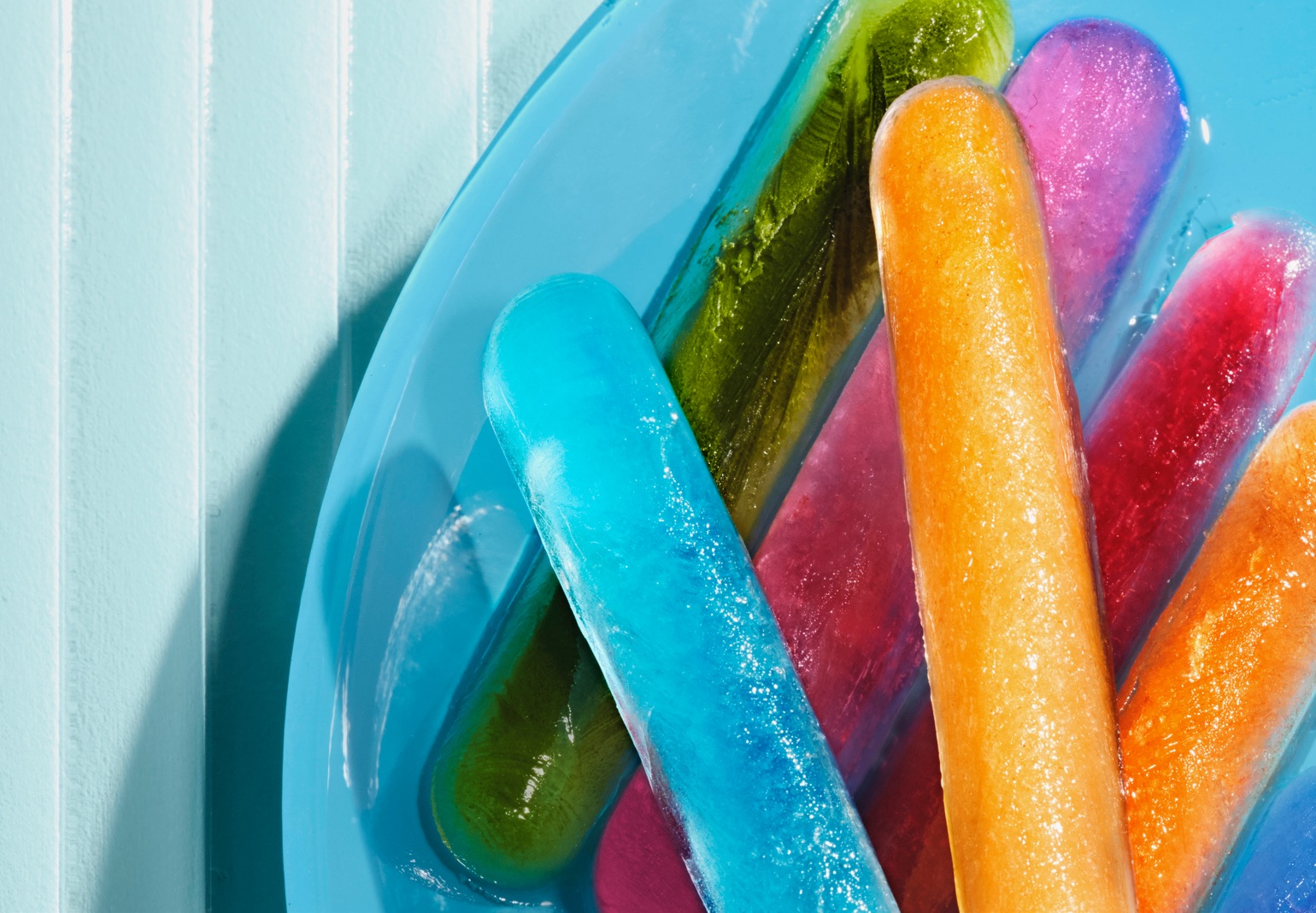 Various colourful popsicles on a blue plate.