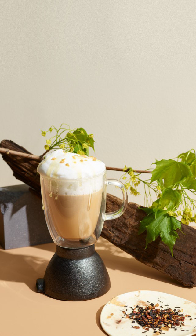 Tasse 16 oz en verre transparent avec chaï latte à la citrouille, petites citrouilles, cubes de caramel et thé en feuilles.